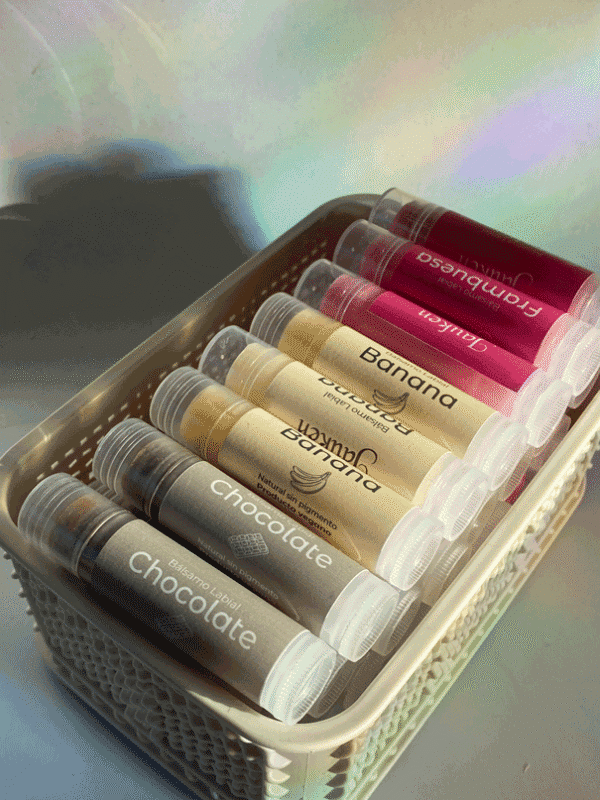 Tubos de balsamo labial de color gris, amarillo y rojo dentro de una canasta de mimbre